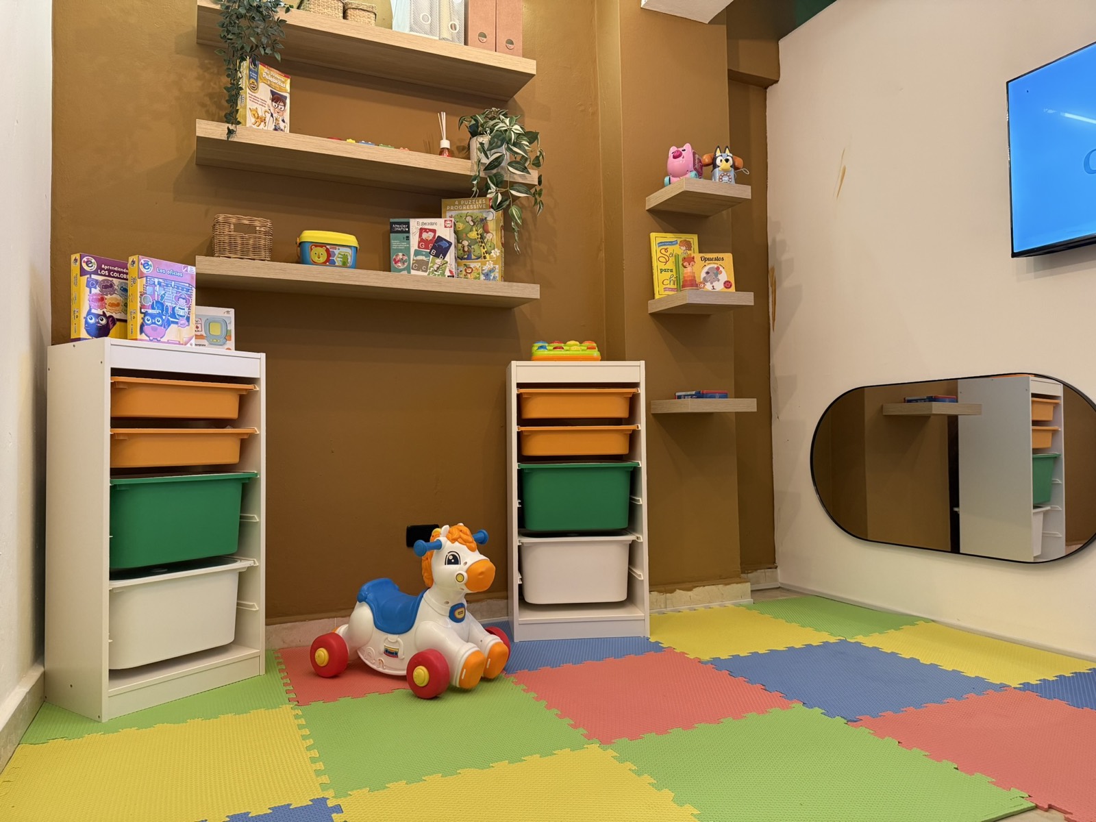 Sala de juego con piso acolchado y estantes de materiales